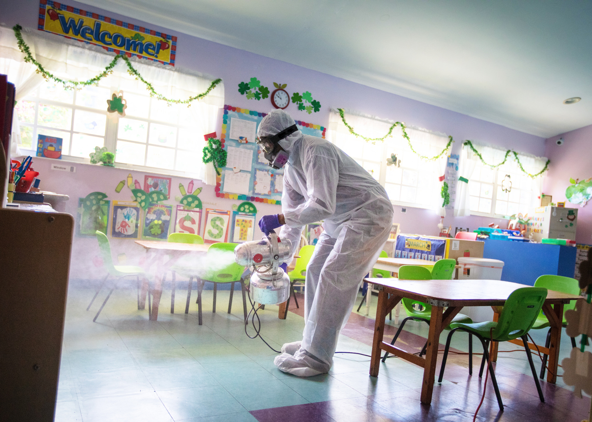 A man disinfecting a classroom as part of reopening daycare facilities post-COVID-19